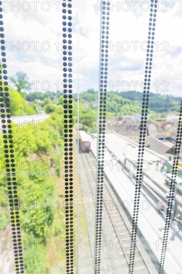 View through a glass wall onto a railway line in a green environment in sunny weather, Zob extension with bridge construction for the new Herman Hesse railway, Calw, Black Forest, Germany
