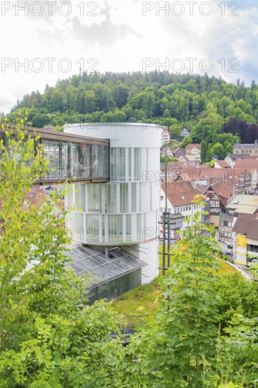 A round modern tower rises above a green, hilly urban landscape, Zob extension with bridge construction for the new Herman Hesse railway, Calw, Black Forest, Germany
