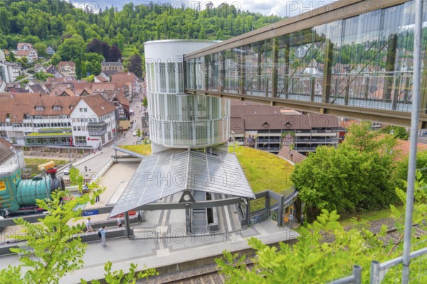 A railway station with a modern glass pedestrian overpass in a small green town, Zob extension with bridge construction for the new Herman Hesse railway, Calw, Black Forest, Germany