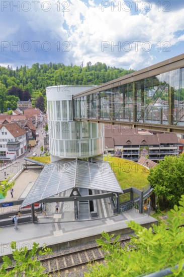 Modern pedestrian bridge over a railway station in a green, small town under a blue sky, Zob extension with bridge construction for the new Herman Hesse railway, Calw, Black Forest, Germany