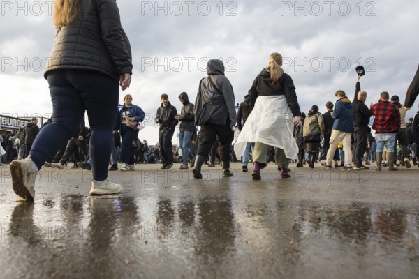 Festival visitors are reflected in a puddle at the Rock am Ring Festival on Sunday, Nürburgring race track race track, 08.06.2025