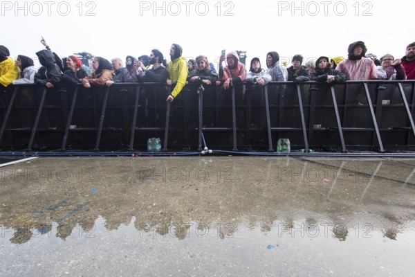 Festival visitors at the barrier are reflected after heavy rain at the Rock am Ring Festival on Friday, Nürburgring race track race track, 07.06.2025