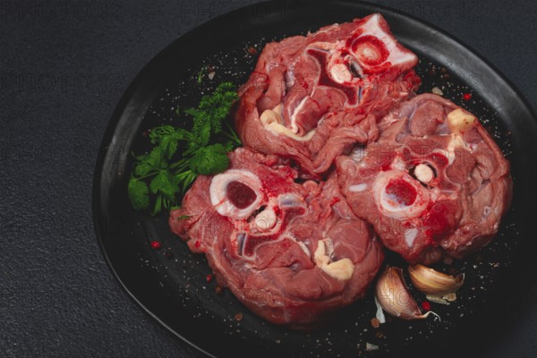 Raw steak, calf's neck on the bone, fresh meat, on a black plate, top view, no people
