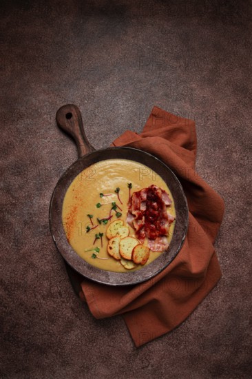 Pumpkin cream soup, curry, fried bacon, bruschetta chips, micro-greens, top view, no people
