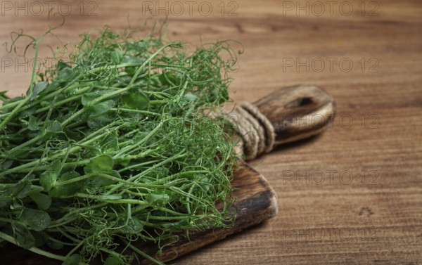 Vibrant green pea sprouts arranged neatly on a rustic wooden cutting board, showcasing their fresh appearance and fine textures under natural lighting