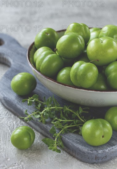 Tkemali, green cherry plum, in a bowl, on a gray table, top view, natural light, no people