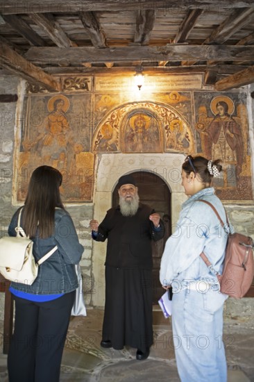 Greek Orthodox priest explains wall paintings from 1802 to visitors, Agia Marina church, Kissos, Pelion peninsula, Thessaly, Greece