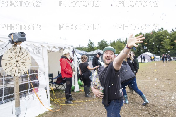 A festival visitor throws confetti on a tent site at the Rock am Ring festival on Saturday, Nürburgring race track race track, 07/06/2025