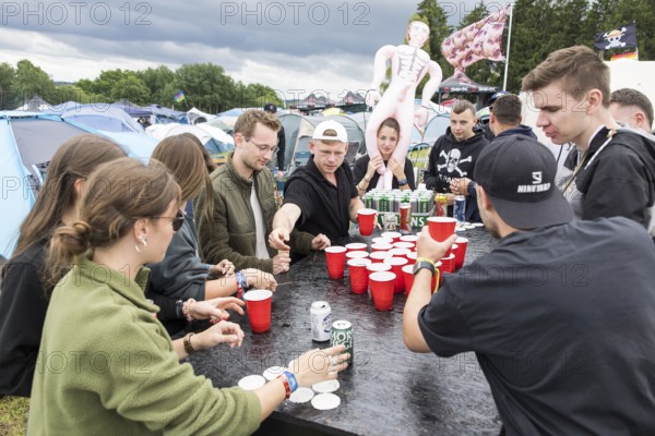 Festival visitors play a drinking game on a campsite at the Rock am Ring Festival on Saturday, Nürburgring race track race track, 07.06.2025
