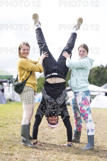 A festival visitor with a handstand thanks to the support of two woman on a camping site at the Rock am Ring Festival on Saturday, Nürburgring race track race track, 07.06.2025