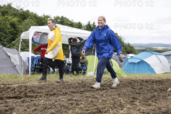 Two festival visitors walk through mud on a campsite at the Rock am Ring Festival on Saturday, Nürburgring race track race track, 07.06.2025
