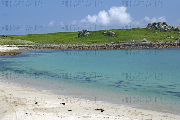 Pristine sandy beach with clear turquoise water and green hill in the background, St Agnes, Isles of Scilly, Cornwall, England, United Kingdom
