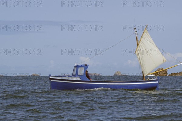 A sailing boat crosses the sea with hoisted sails under a blue sky, fishing, St Agnes, Isles of Scilly, Cornwall, England, United Kingdom