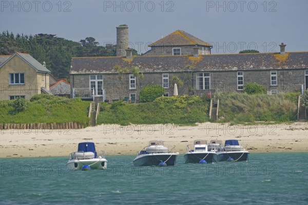 Four small boats close to the beach in front of traditional houses in an idyllic setting, Tresco, Isles of Scilly, Cornwall, England, United Kingdom
