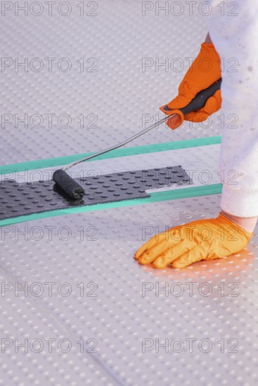 Close-up of a gloved hand using a paint roller on the floor, renovation of the swimming lines, Calw Stammheim outdoor pool, Calw, Black Forest, Germany