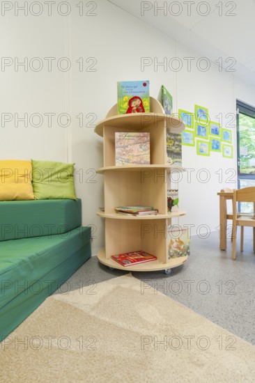 Children's room with bookshelf and sofa, colourful cushions and decorative pictures on the wall, transitional daycare centre in container construction, Gechingen daycare centre, Calw district, Germany