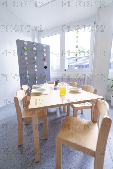 Modern dining area with wooden furniture and colourful window decorations, transitional daycare centre in container construction, Gechingen daycare centre, Calw district, Germany