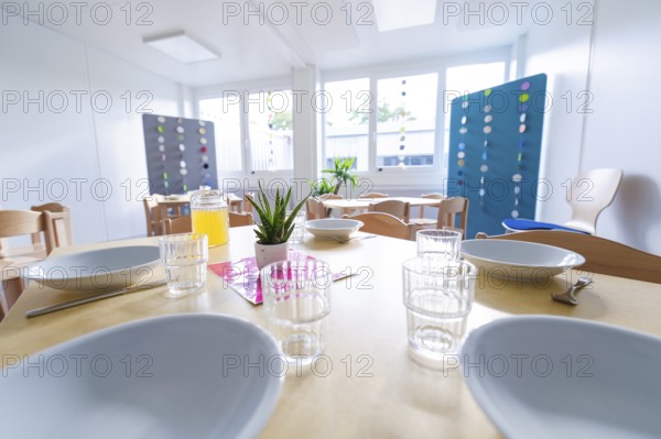 Light-flooded dining area with prepared plates and a juice jug on the table, transitional containerised daycare centre, Gechingen daycare centre, Calw district, Germany