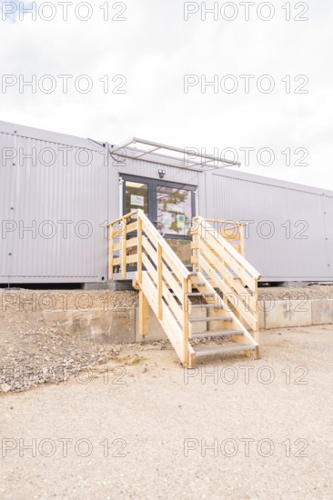 Modern entrance to a grey modular building with wooden stairs, transitional daycare centre in container construction, Gechingen daycare centre, Calw district, Germany