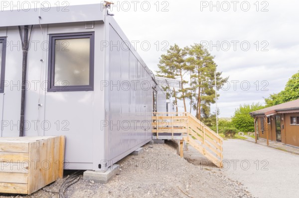 Exterior view of a grey modular building with trees in the background, transitional daycare centre in container construction, Gechingen daycare centre, Calw district, Germany
