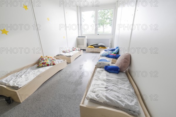 A bright bedroom with several small beds and colourful cushions, transitional daycare centre in container construction, Gechingen daycare centre, Calw district, Germany