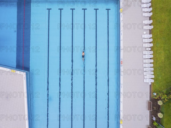 Drone shot of an empty swimming pool with a swimmer in a turquoise-coloured pool on a summer's day, Calw outdoor pool, Black Forest, Germany