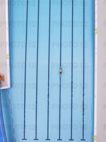 A single swimmer swims in an empty blue pool, Calw outdoor pool, Black Forest, Germany