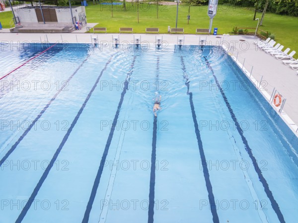 A swimmer swimming his laps in a large, empty swimming pool, Calw outdoor pool, Black Forest, Germany