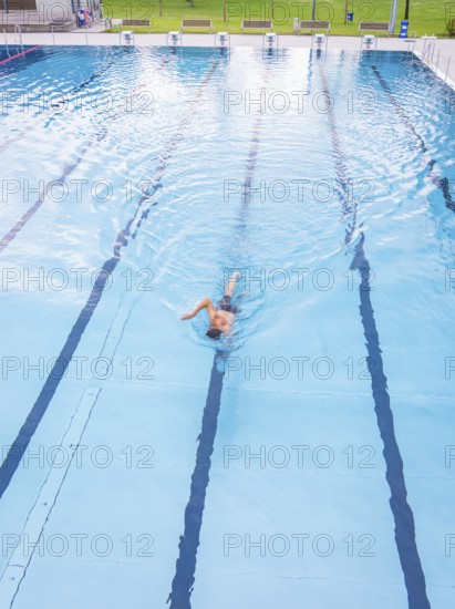 A person swims alone in an almost empty pool along the lanes, Calw outdoor pool, Black Forest, Germany