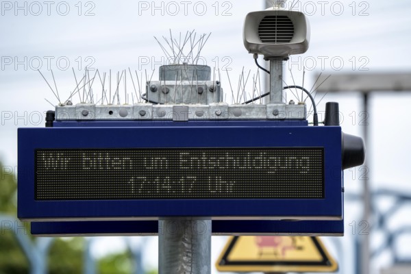 Display board, at a station, train cancellation announcement due to construction work, display shows text with apology for the train cancellation, peppered with thin wires against birds, pigeons, to keep the technical equipment free of bird droppings, bird defence, pigeon defence