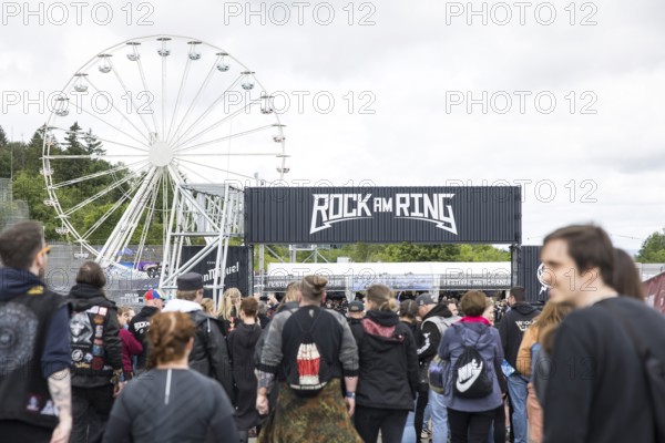Festival visitors in front of a Ferris wheel and a container with the Rock am Ring logo at the Rock am Ring Festival on Friday, Nürburgring race track race track, 06/06/2025