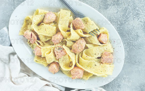 Papardelle pasta, in creamy sauce with salmon, natural light, lifestyle, homemade, on a gray background, no people