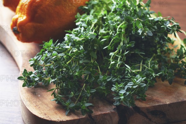 Lemon thyme, on a wooden chopping board, with lemons, close-up