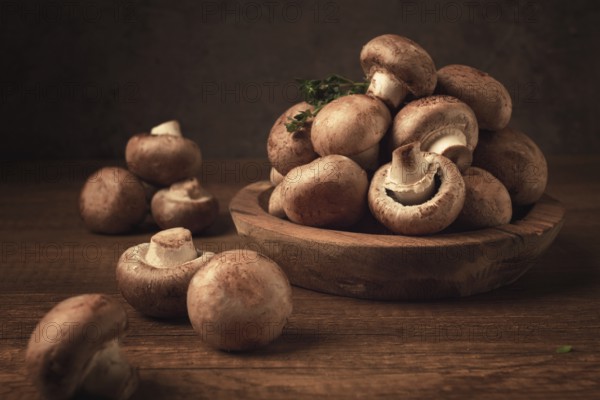 Brown champignons, royal mushrooms, in a wooden bowl, on a wooden table