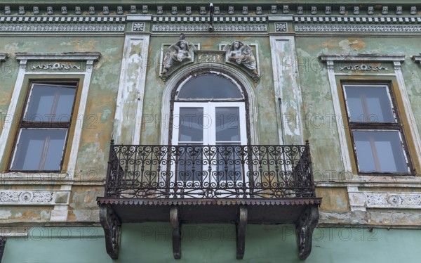 Dilapidated 19th century house with sculptures above the rusty balcony, Medias, Romania