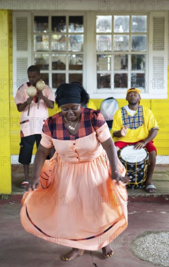 Guatemalan woman in traditional dress singing and dancing, men playing music in the back, Garifuna people, Livingston, Izabal Department, Guatemala