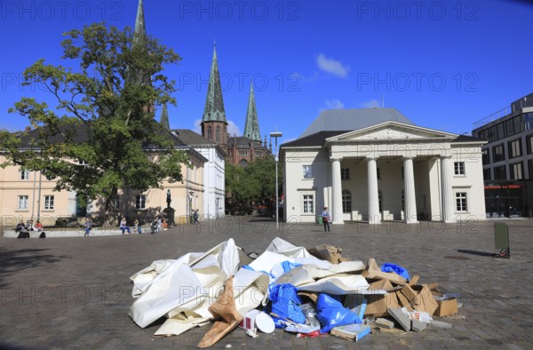 Schlossplatz with castle guard and St. Lambert's Church in the background, in the foreground a heap of waste paper, trash, remnants of an event, Oldenburg, Lower Saxony, Germany