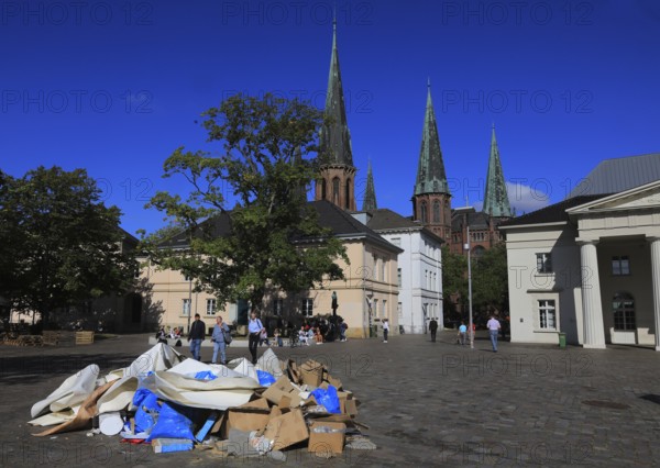 Schlossplatz with castle guard and St. Lambert's Church in the background, in front of it a pile of waste paper, remnants from an event, Oldenburg, Lower Saxony, Germany