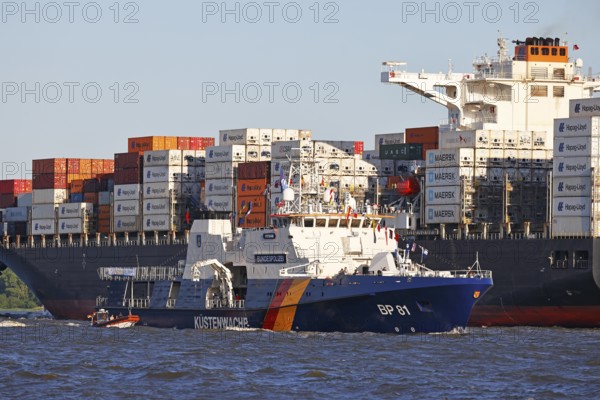 Decorated ship of the German Coast Guard and Federal Police BP 81 Potsdam leaves the Port of Hamburg on the Elbe after Hamburg's port birthday, behind it container ship sails up the Elbe towards the Port of Hamburg, shipping on the Elbe, Wedel, Schleswig-Holstein, Germany