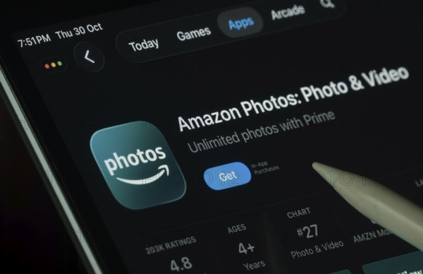 Dhaka, Bangladesh- 30 Oct 2025: Amazon photos app displayed on a iPad screen in dark mode with a digital pen pointing at it