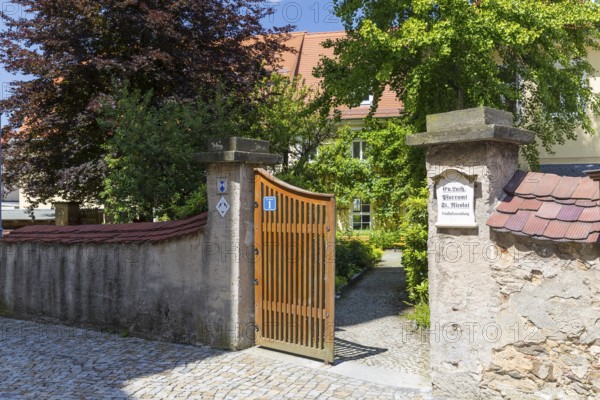 Entrance to the parish office of St. Nicolai through a gate through the wall, behind it historic buildings with gardens, Pulsnitz, Saxony, Germany