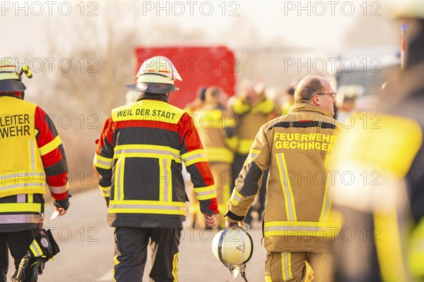 Firemen in yellow and red uniforms walk on a country road, accompanied by colleagues, fire brigade exercise on the Hermann Hesse Railway, Ostelsheim, Calw district, Germany