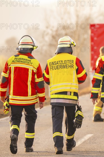 Firefighters walk together on a street, operational clothing and equipment visible, fire brigade exercise on the Hermann Hesse Railway, Ostelsheim, Calw district, Germany