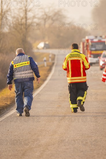 Rescue workers walk on a country road while emergency vehicles are visible in the background, fire brigade exercise on the Hermann Hesse Railway, Ostelsheim, Calw district, Germany
