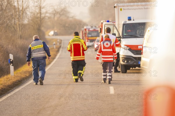 Emergency personnel from various services walk on a country road, accompanied by emergency vehicles, fire brigade exercise on the Hermann Hesse Railway, Ostelsheim, Calw district, Germany