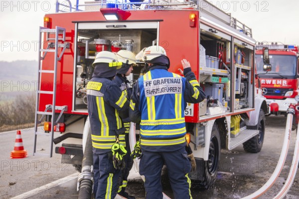 Firemen in emergency clothing stand at an emergency vehicle and check hoses, fire brigade exercise on the Hermann Hesse Railway, Ostelsheim, Calw district, Germany