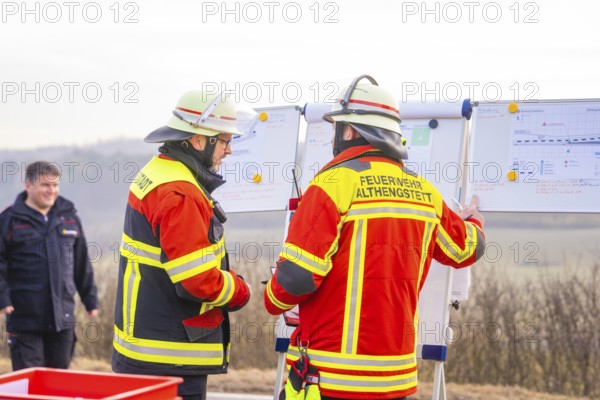 Firefighters in operational clothing during mission briefing in front of a rural backdrop, fire brigade exercise on the Hermann Hesse Railway, Ostelsheim, Calw district, Germany