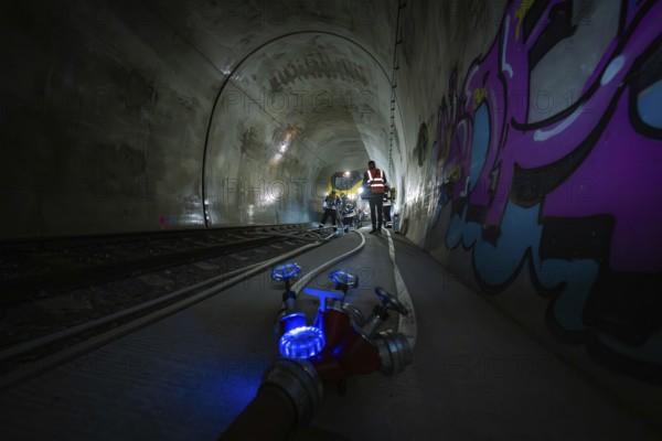 People work in the dark tunnel. Technical equipment and colorful graffiti on the walls, fire department exercise on the Hermann Hesse railway, Ostelsheim, Germany