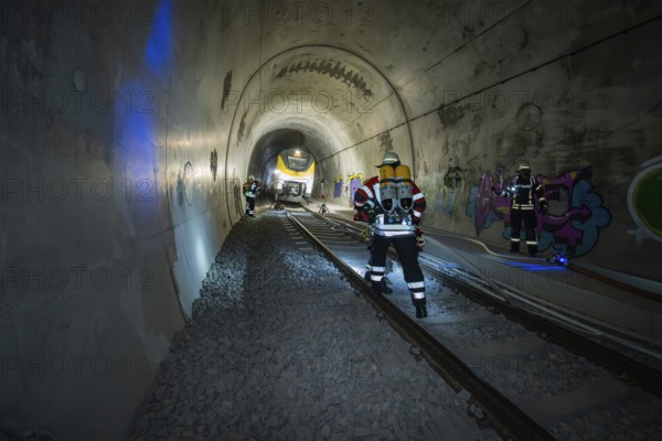Firefighters working in an illuminated tunnel with graffiti, fire brigade exercise on the Hermann Hesse railway, Ostelsheim, Germany