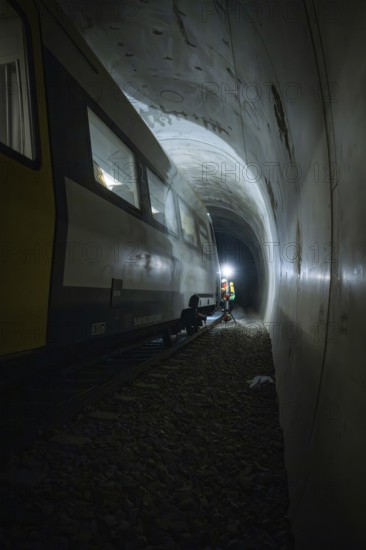 Light beam illuminates workers next to a train in a dark tunnel, fire department exercise on the Hermann Hesse Railway, Ostelsheim, Germany